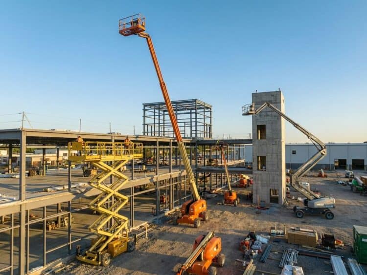 Luchtfoto van verschillende hoogwerkers op bouwplaats: schaarliften, telescoopliften en knikarmliften op verschillende hoogtes
