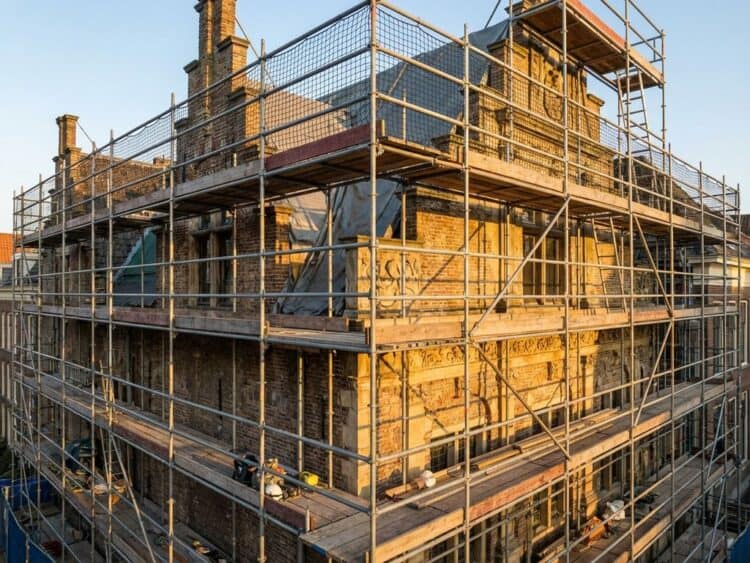 Steiger rond historisch Nederlands monument tijdens restauratiewerkzaamheden met gouden uurtje verlichting