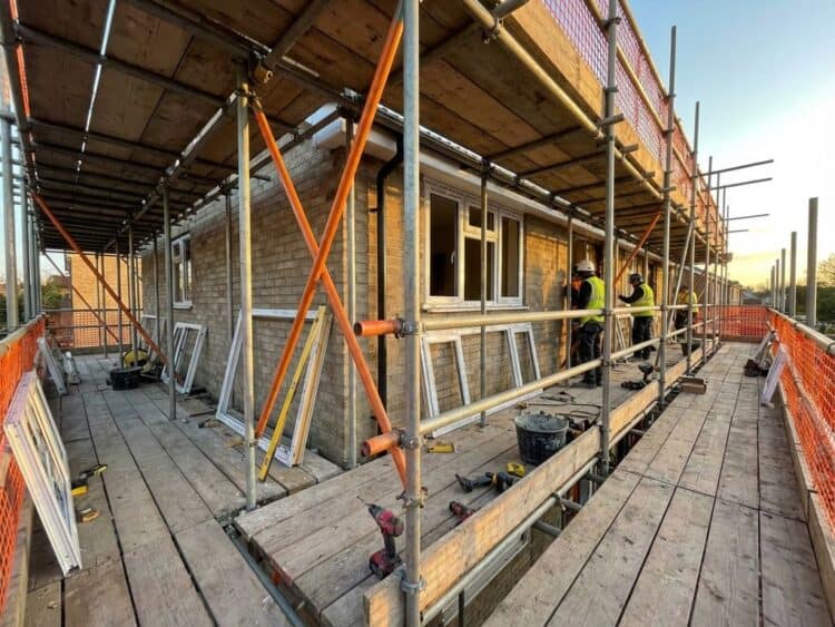 Steiger rond huis tijdens raamkozijn vervanging met professionele gereedschappen en dramatische gouden uurverlichting