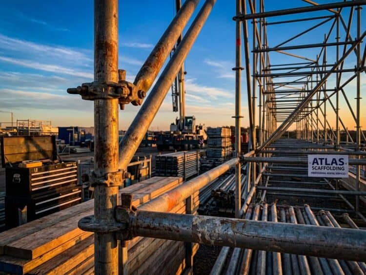 Robuuste metalen steigerstructuren met stalen buizen en klemmen tijdens gouden uur met dramatische blauwe lucht