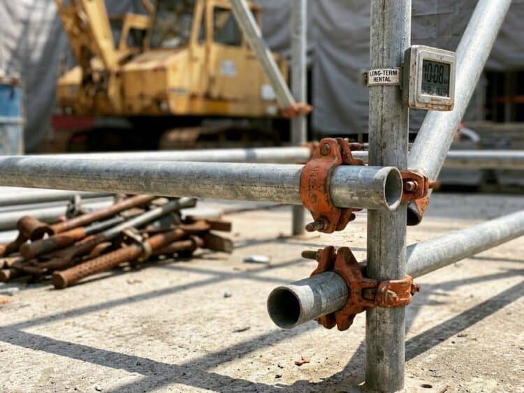 Robuuste metalen steigerbuizen en klemmen op bouwplaats met oranje veiligheidselementen en gegalvaniseerd staal