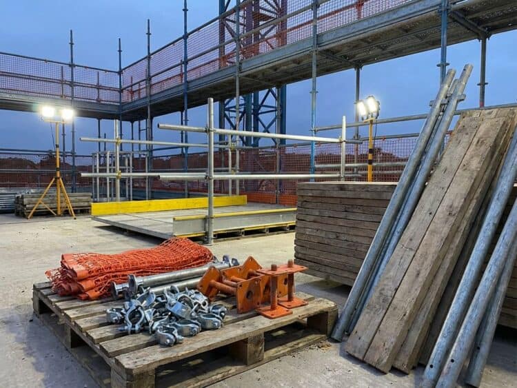 Steigeraccessoires op bouwplaats met chroomstalen klemmen, veiligheidsrailing, houten planken en beschermingsnetten