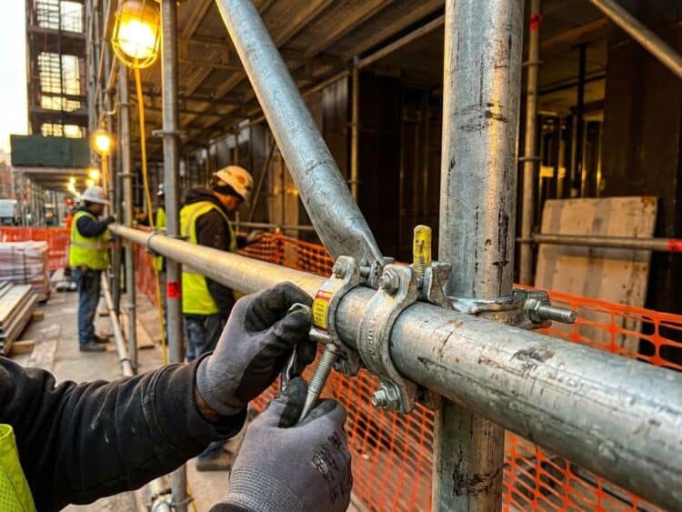 Metalen leuningen bevestigd aan huursteigers met professionele klemmen en veiligheidsverbindingen op bouwplaats